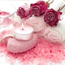 Kerze mit gerollten Handtüchern und Rosen